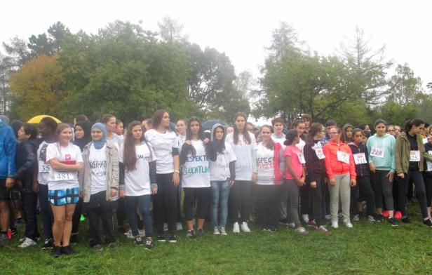 Eine Gruppe junger Menschen steht für ein Rennen bereit, viele tragen T-Shirts mit Aufschriften zum Thema Flüchtlinge.