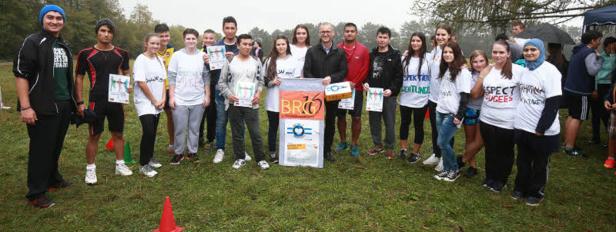 Eine Gruppe von Menschen steht auf einer Wiese und hält Schilder und Auszeichnungen.