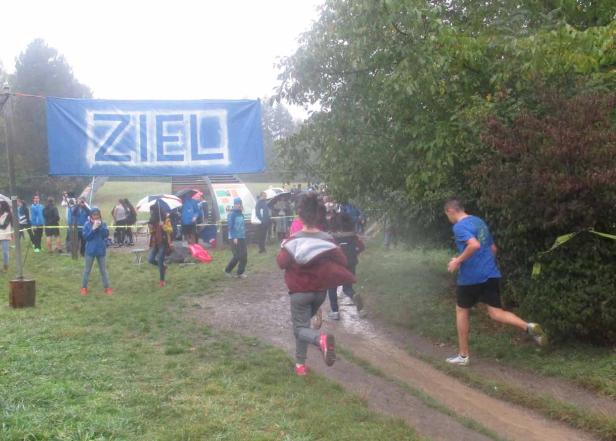 Ein Laufrennen bei regnerischem Wetter mit einem „Ziel“-Banner im Hintergrund.