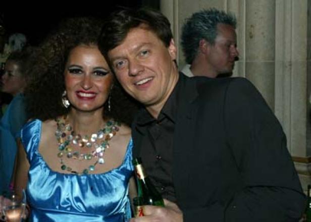 Eine Frau mit Afro-Frisur und ein Mann mit einer Flasche posieren für ein Foto.