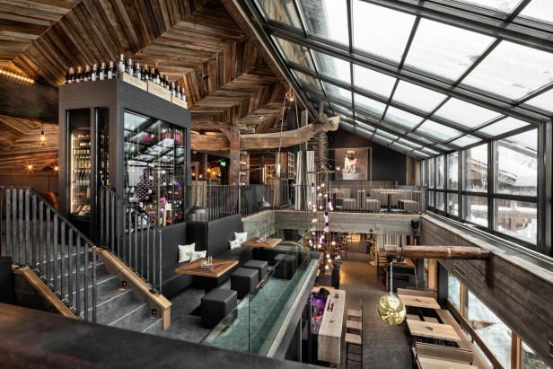 Innenansicht eines luxuriösen Restaurants mit rustikalem Holzdesign und grossen Fenstern.