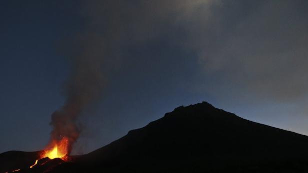 Ein Vulkan bricht in der Dämmerung aus und speit Lava und Rauch aus.