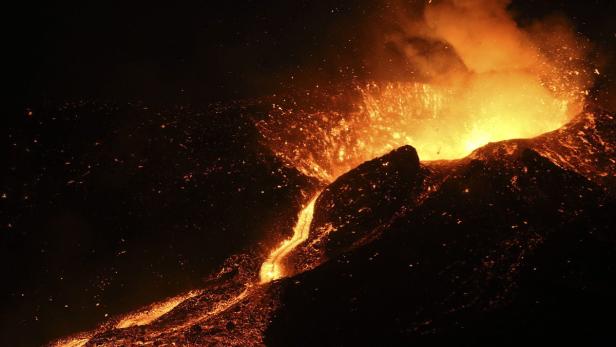 Ein Vulkan bricht nachts aus und speit Lava und Asche.