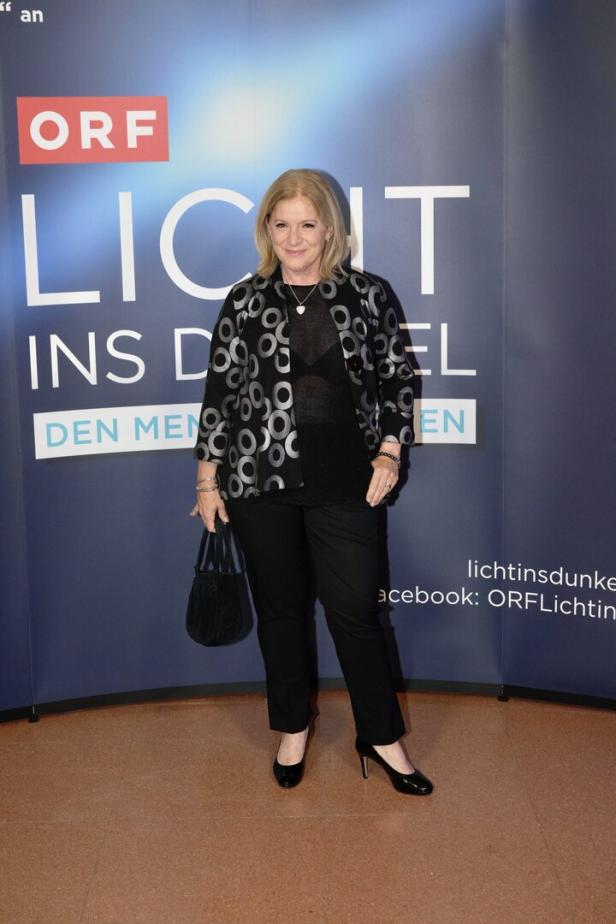 Eine Frau posiert vor einem "Licht ins Dunkel"-Hintergrund des ORF.