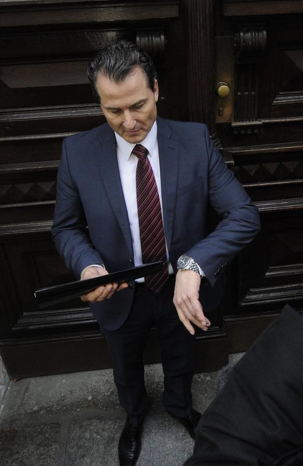 Ein Mann im Anzug blickt auf seine Armbanduhr.