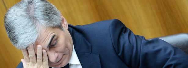 Ein Mann in einem Anzug hält seine Hand an die Stirn.