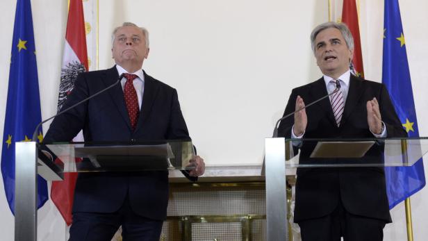 Zwei Männer stehen an Rednerpulten vor den Flaggen Österreichs und der EU.