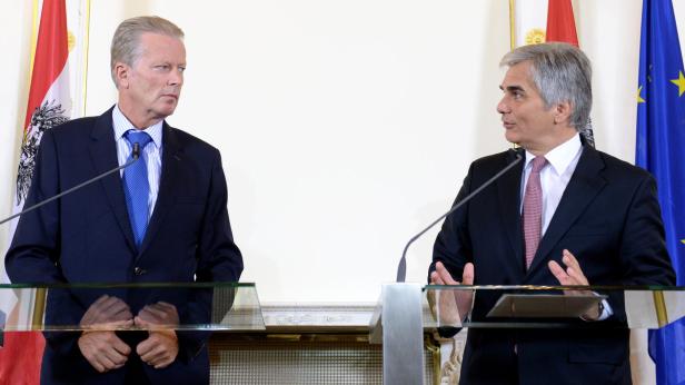 Zwei Männer in Anzügen stehen an Rednerpulten vor österreichischen und EU-Flaggen.