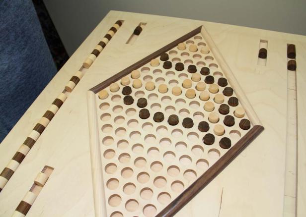 Ein Holzbrettspiel mit hellen und dunklen Spielsteinen in einem dreieckigen Feld.