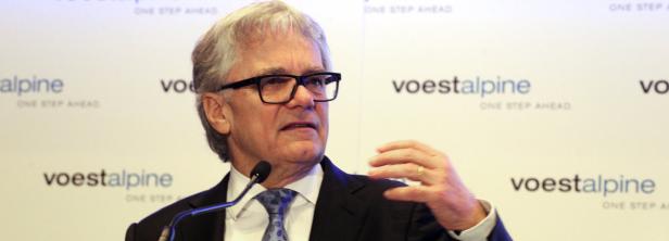 Ein Mann mit Brille spricht vor einem Hintergrund mit dem Voestalpine-Logo.