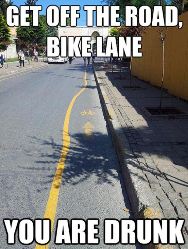 Ein gelber Radweg verläuft kurvenreich auf einer Straße.