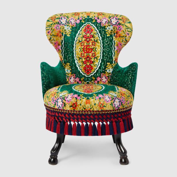 Ein mit Blumenmuster verzierter Sessel mit Quasten an der Unterseite des Sitzes.