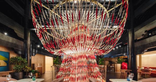 Eine große, dekorative Installation aus roten, goldenen und weißen Bändern hängt in einem Restaurant.