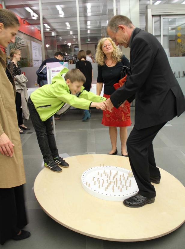 Ein Junge und ein Mann balancieren auf einer Drehscheibe mit Hindernissen.