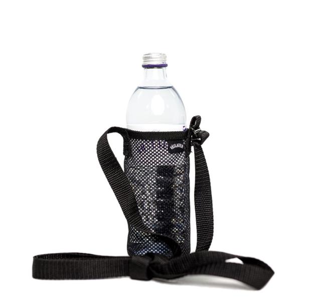 Eine Glasflasche Vöslauer in einer schwarzen Netzstofftasche mit Tragegurt.