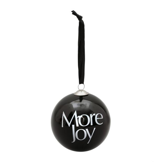 Eine schwarze Weihnachtskugel mit der Aufschrift „More Joy“ hängt an einem Band.