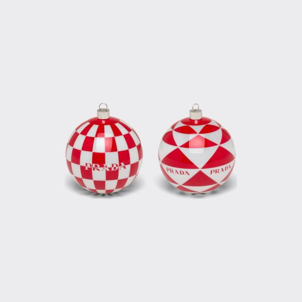 Zwei rote und weiße Weihnachtskugeln von Prada vor einem weißen Hintergrund.