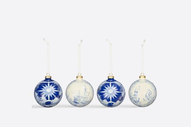 Vier Weihnachtskugeln mit blauen Motiven von Sternen und Segelschiffen.