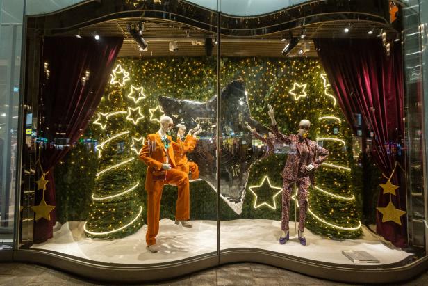 Ein Schaufenster mit zwei Schaufensterpuppen in Anzügen vor einem weihnachtlichen Hintergrund.