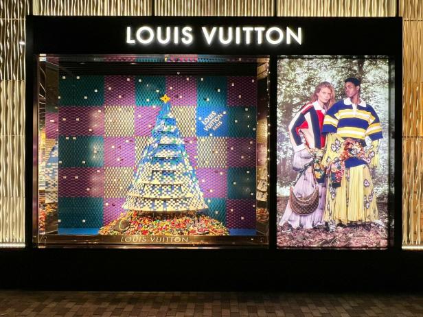 Ein Louis Vuitton Schaufenster mit einem Weihnachtsbaum aus bunten Accessoires und zwei Models.