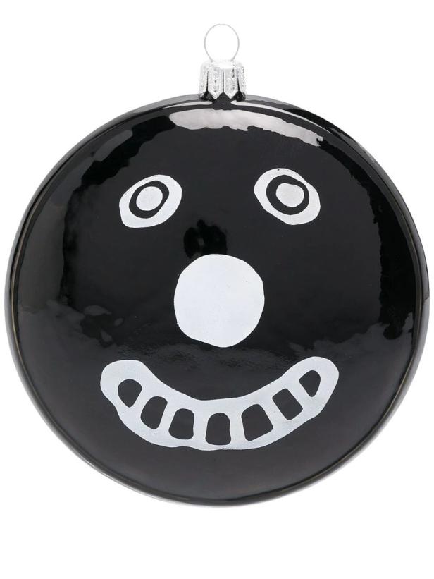 Eine schwarze Weihnachtskugel mit einem weißen, stilisierten Gesicht.