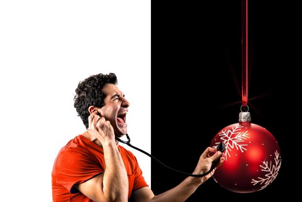 Ein Mann „untersucht“ eine rote Weihnachtskugel mit einem Stethoskop.