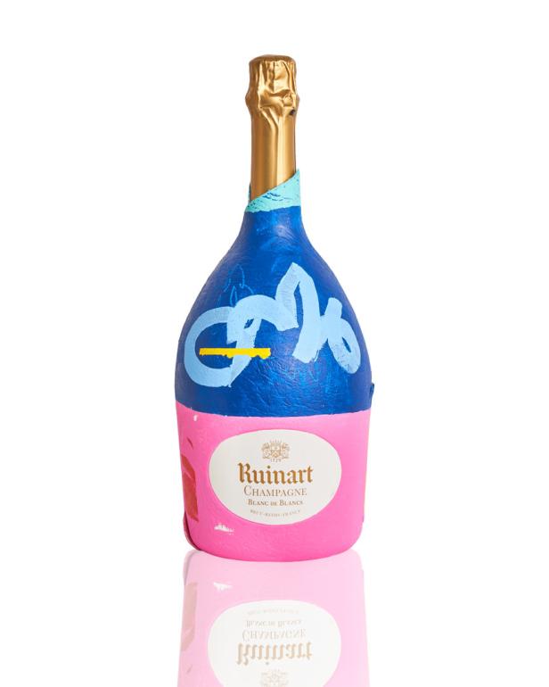 Eine bemalte Champagnerflasche von Ruinart mit blauen, rosa und goldenen Farbtönen.