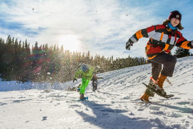Kinder spielen im Schnee und bewerfen sich mit Schneebällen.