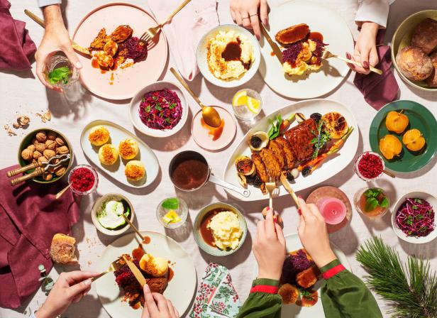 Ein festliches Mahl mit Braten, Rotkohl, Klößen und verschiedenen Beilagen auf einem Tisch angerichtet.