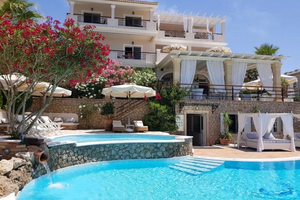 Ein luxuriöses Hotel mit Pool und blühenden Büschen im Außenbereich.