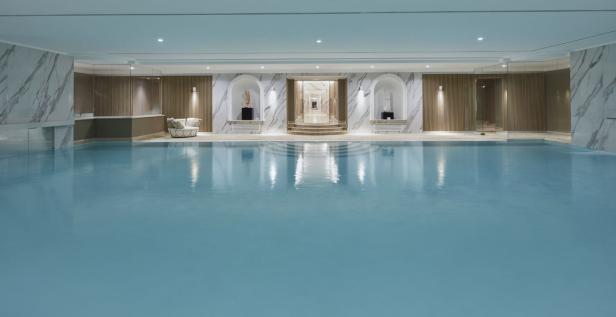 Ein Innenpool mit hellblauem Wasser in einem luxuriösen Spa.