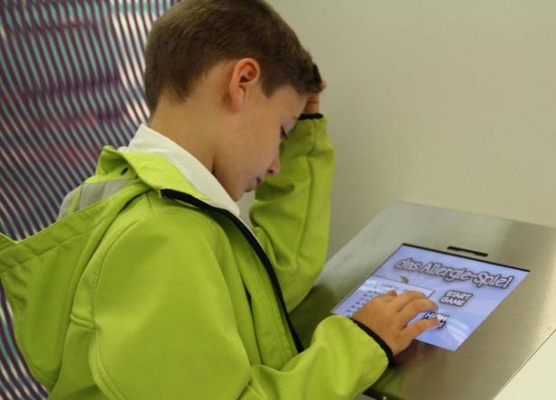 Ein Junge spielt „Das Allergie-Spiel“ auf einem interaktiven Bildschirm.