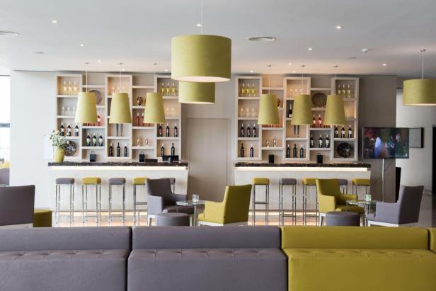 Eine Bar mit Hockern, Regalen voller Flaschen und einer Sitzecke mit Sofas.
