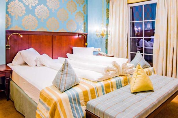 Ein Hotelzimmer mit einem Doppelbett, einem Fenster und einer gemusterten Tapete.