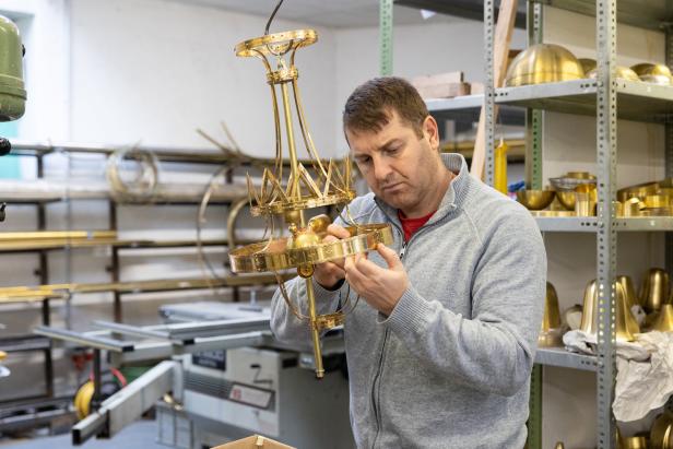 Ein Mann montiert eine goldene Lampe in einer Werkstatt.