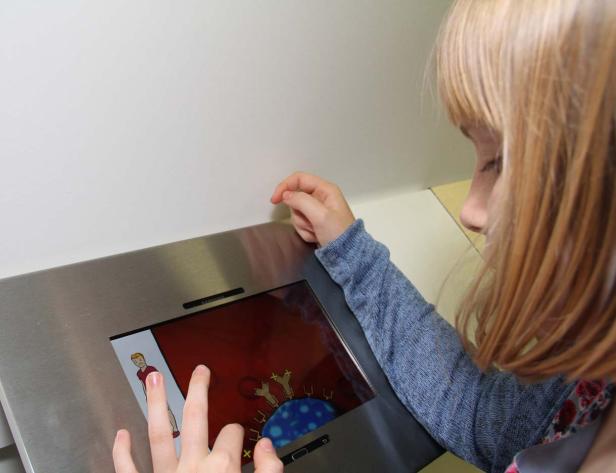 Ein Mädchen interagiert mit einem interaktiven Bildschirm, der eine medizinische Animation zeigt.