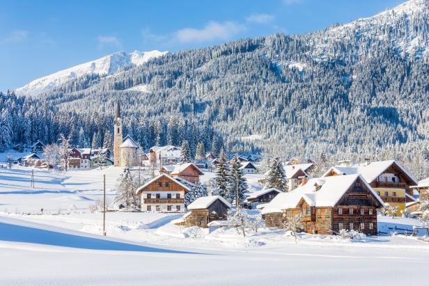 Dörfliche Winterlandschaft in Österreich, schneebedeckte Berge und Häuser.