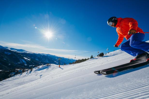 Ein Skifahrer fährt auf einer präparierten Piste an einem sonnigen Tag.