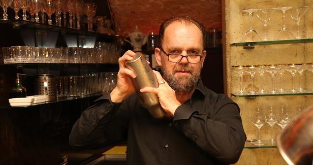 Ein Barkeeper mixt einen Cocktail in einem Shaker hinter einer Bar.