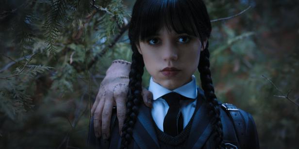 Jenna Ortega als Wednesday Addams mit „Things“ Hand auf ihrer Schulter.