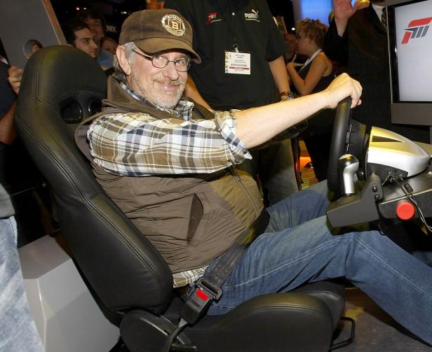 Steven Spielberg sitzt in einem Rennsimulator und lächelt.