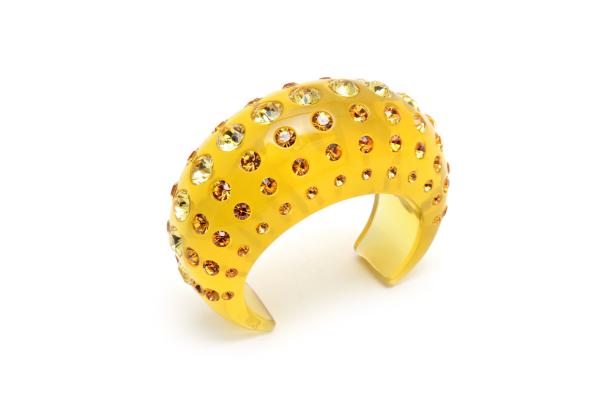 Ein gelbes Armband, besetzt mit gelben und orangefarbenen Strasssteinen.