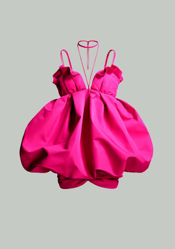 Ein leuchtend pinkfarbenes, kurzes Kleid mit Rüschen und Ballonrock vor grauem Hintergrund.
