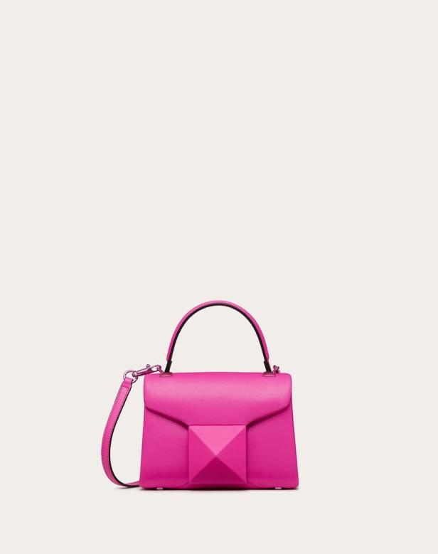 Eine pinkfarbene Handtasche mit einem pyramidenförmigen Detail auf der Vorderseite.