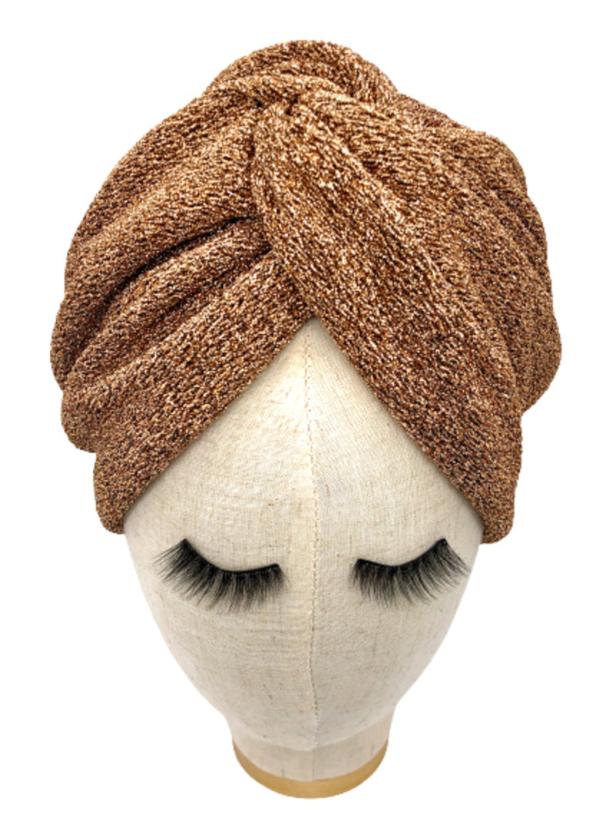 Ein goldfarbener Turban auf einem Schaufensterpuppenkopf mit langen falschen Wimpern.