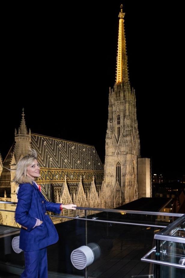 Eine Frau vor dem beleuchteten Stephansdom in Wien bei Nacht.