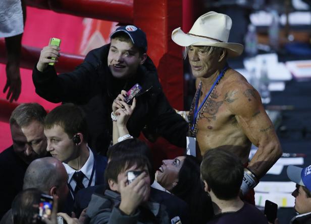Mickey Rourke steht mit Cowboyhut im Boxring und wird von Fans fotografiert.