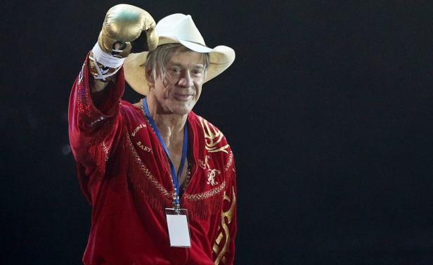 Mickey Rourke mit Cowboyhut und Boxhandschuhen bei einem Boxkampf.