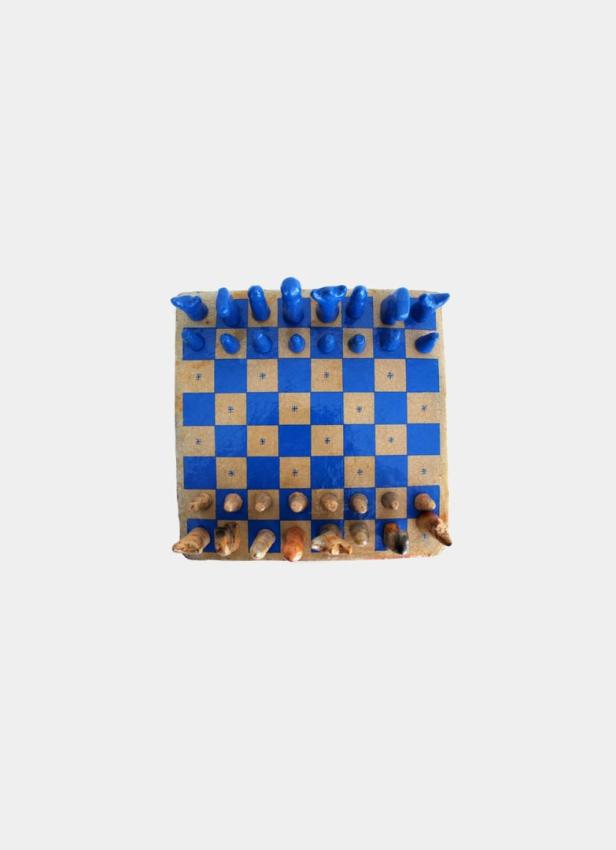Ein Schachbrett mit blauen und beigen Feldern und handgefertigten Schachfiguren.
