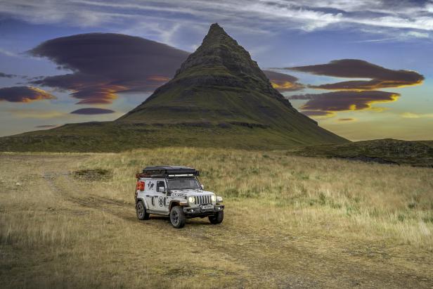 Ein Geländewagen fährt vor dem Berg Kirkjufell in Island.
